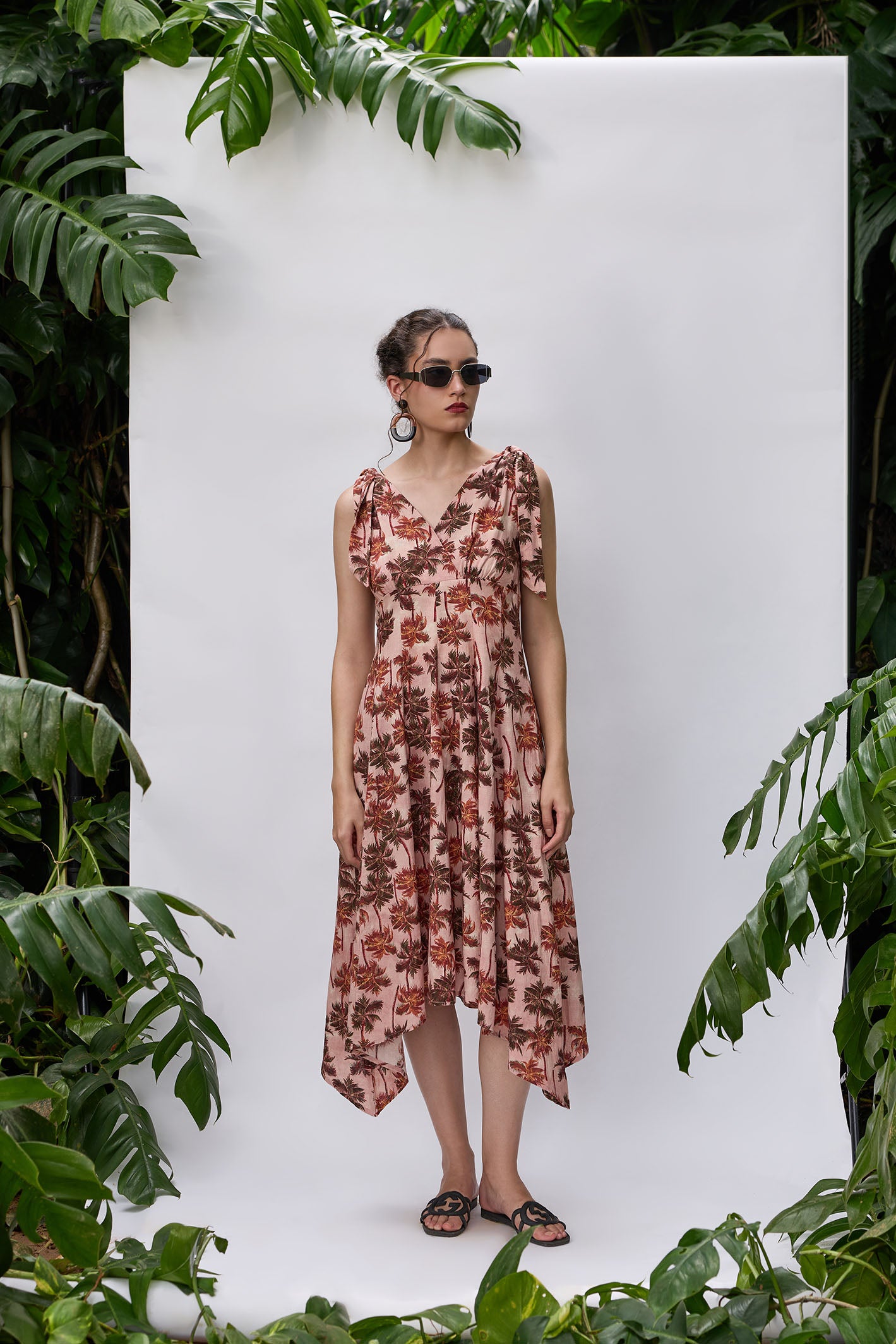 Woman wearing blush palm print empire waist dress with asymmetrical hem – VA RA