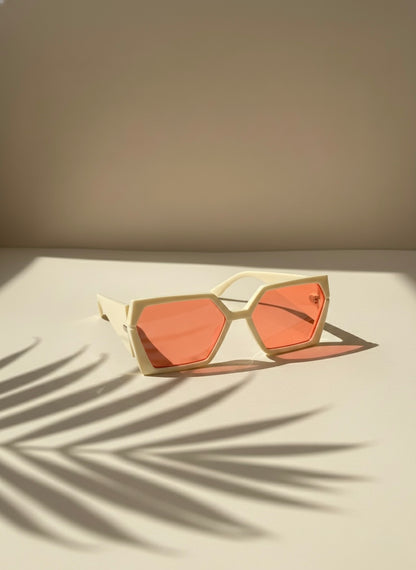 Cream geometric sunglasses with peach-pink lenses placed under soft palm shadows — Peach Bellini Sunglasses by VA RA.