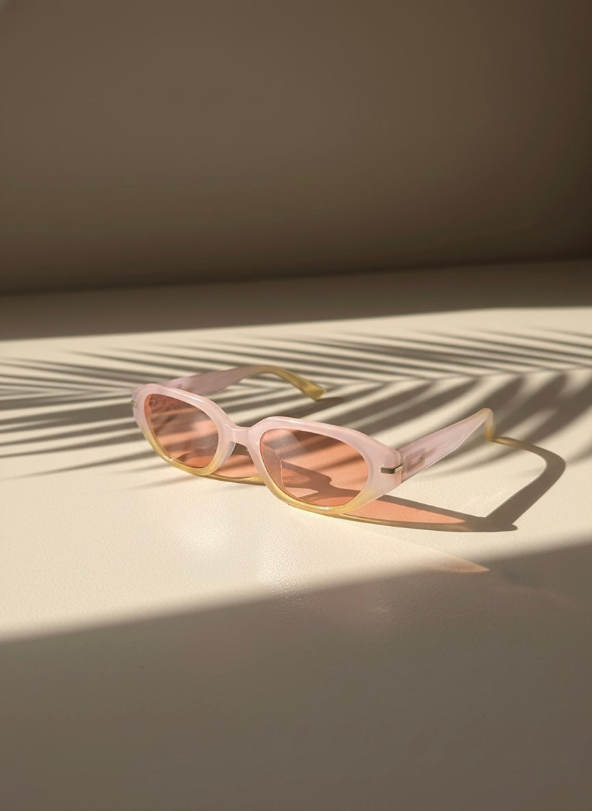 Pina Colada Sunglasses with smoky lenses resting on a sunlit surface with palm shadows — VA RA 